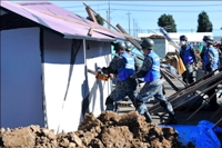 写真：倒壊した家を壊し救助訓練する様子