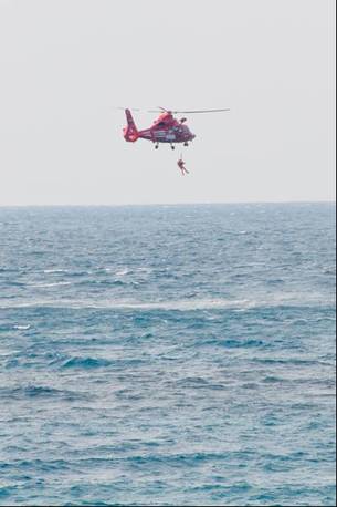 写真：ヘリコプターからのびたワイヤーで救助される様子2