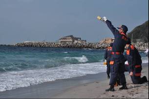 写真：海辺から海に向かって信号を送る隊員