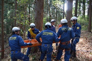 写真：山林で担架を運ぶ消防団員たち