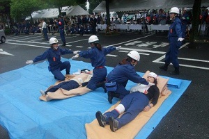 写真：横たわるけが人を救護する女性隊。応急救護訓練の様子 