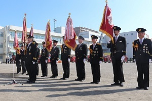 写真：屋外で旗を持ち整列する消防団員